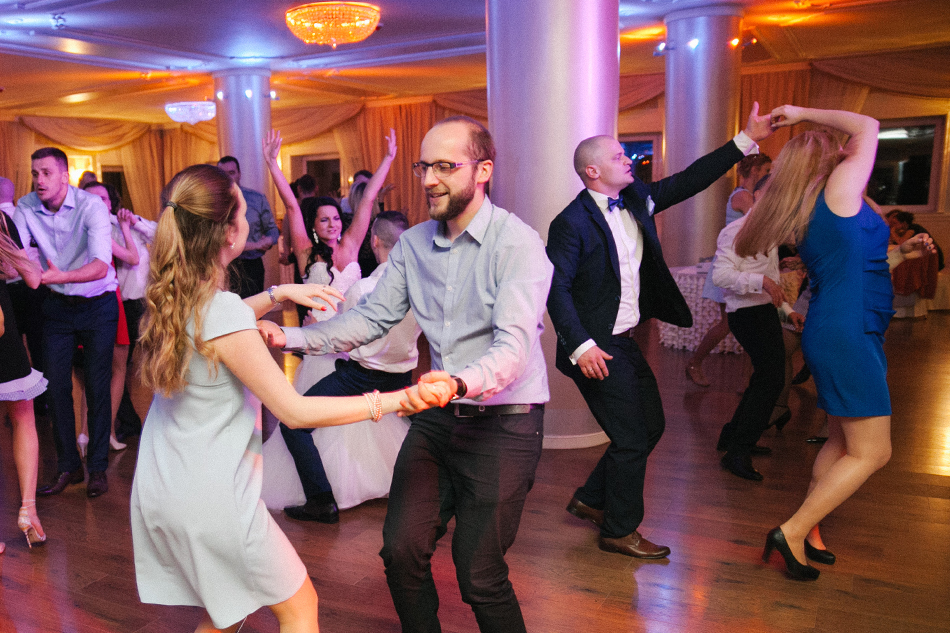 goście i para młoda tańczą na sali weselnej
